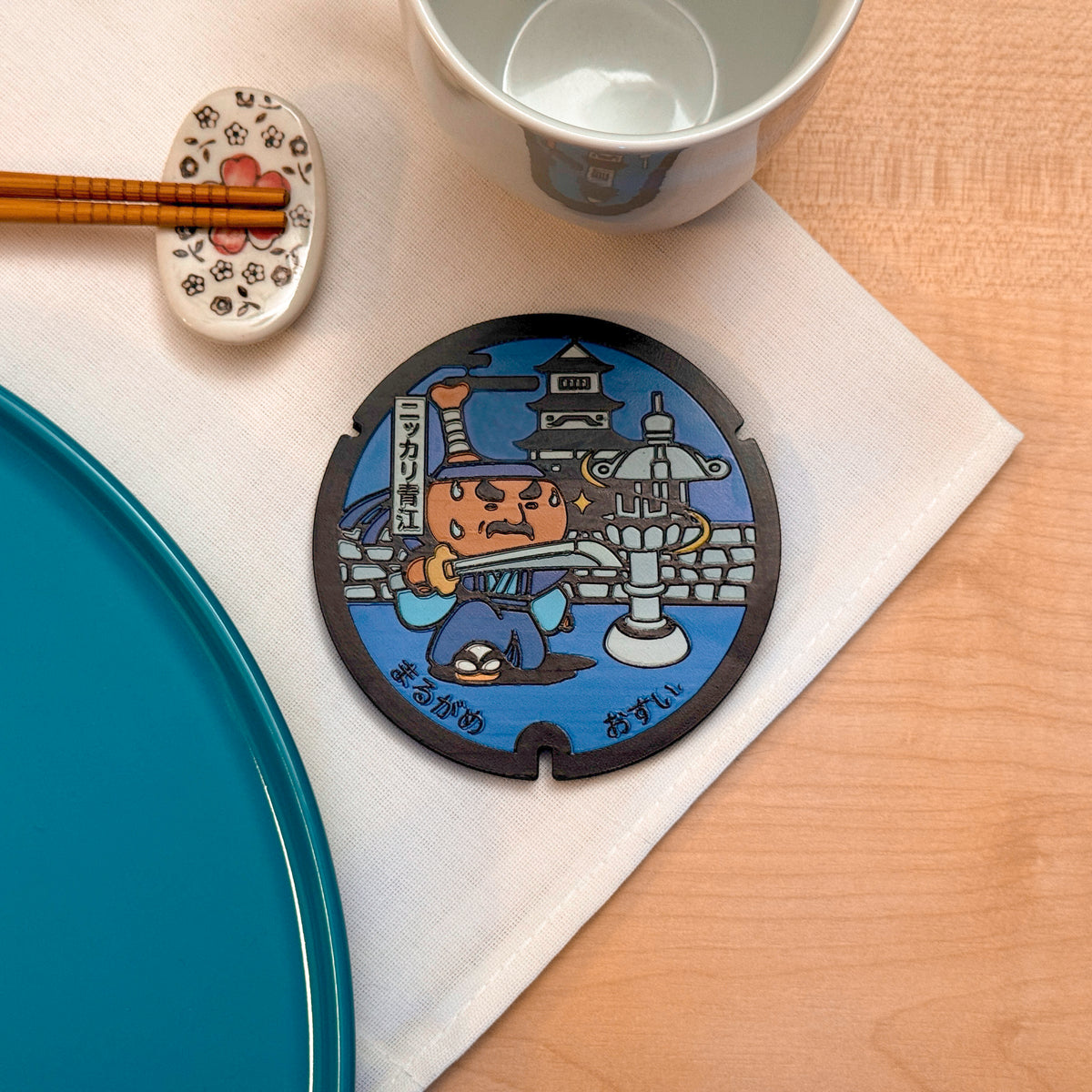 Sottobicchiere ROJI collezione Miti con il design del tombino di Bone-tsuki Juju e la spada Nikkari Aoe, Marugame